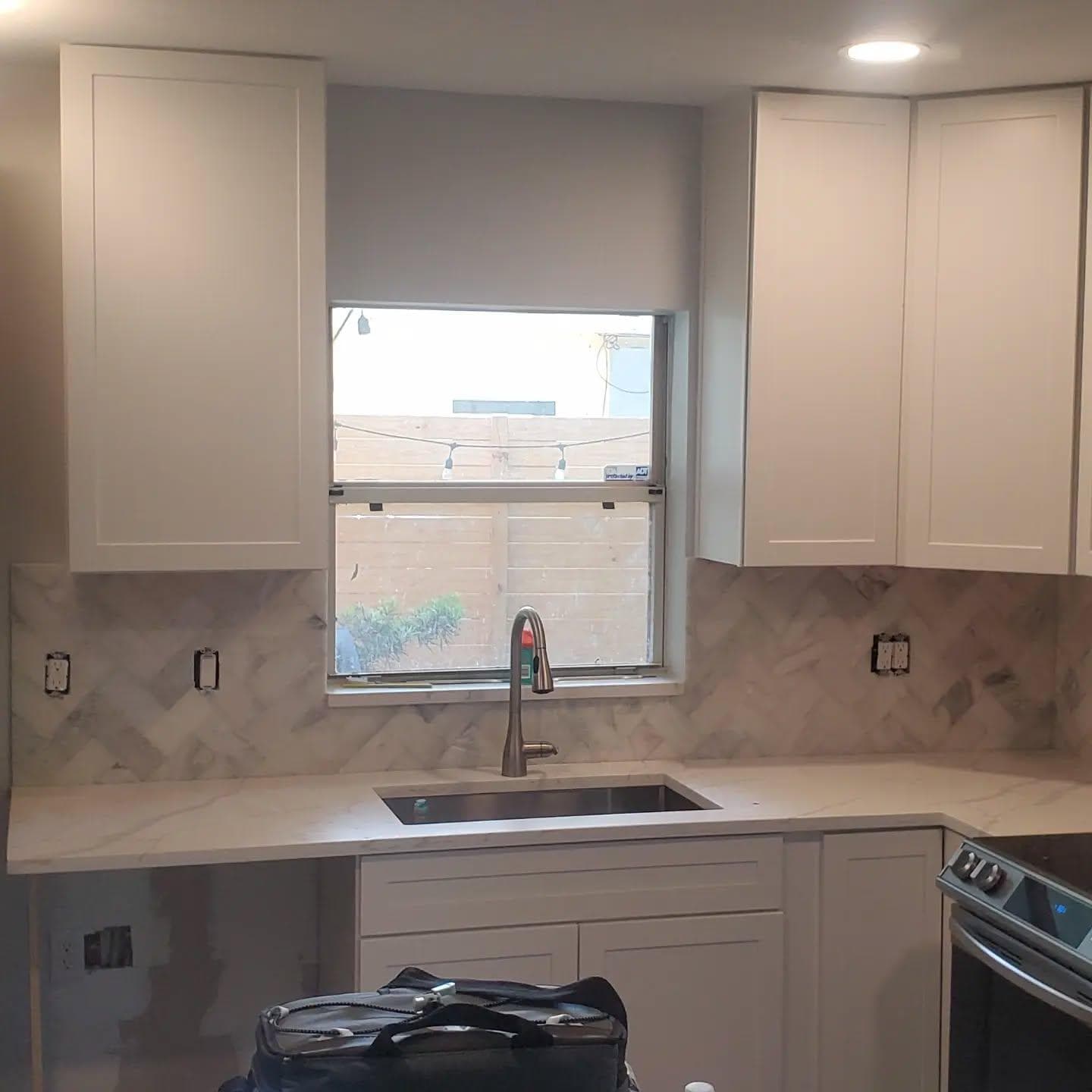 Woven metallic mosaic tile backsplash over granite counter