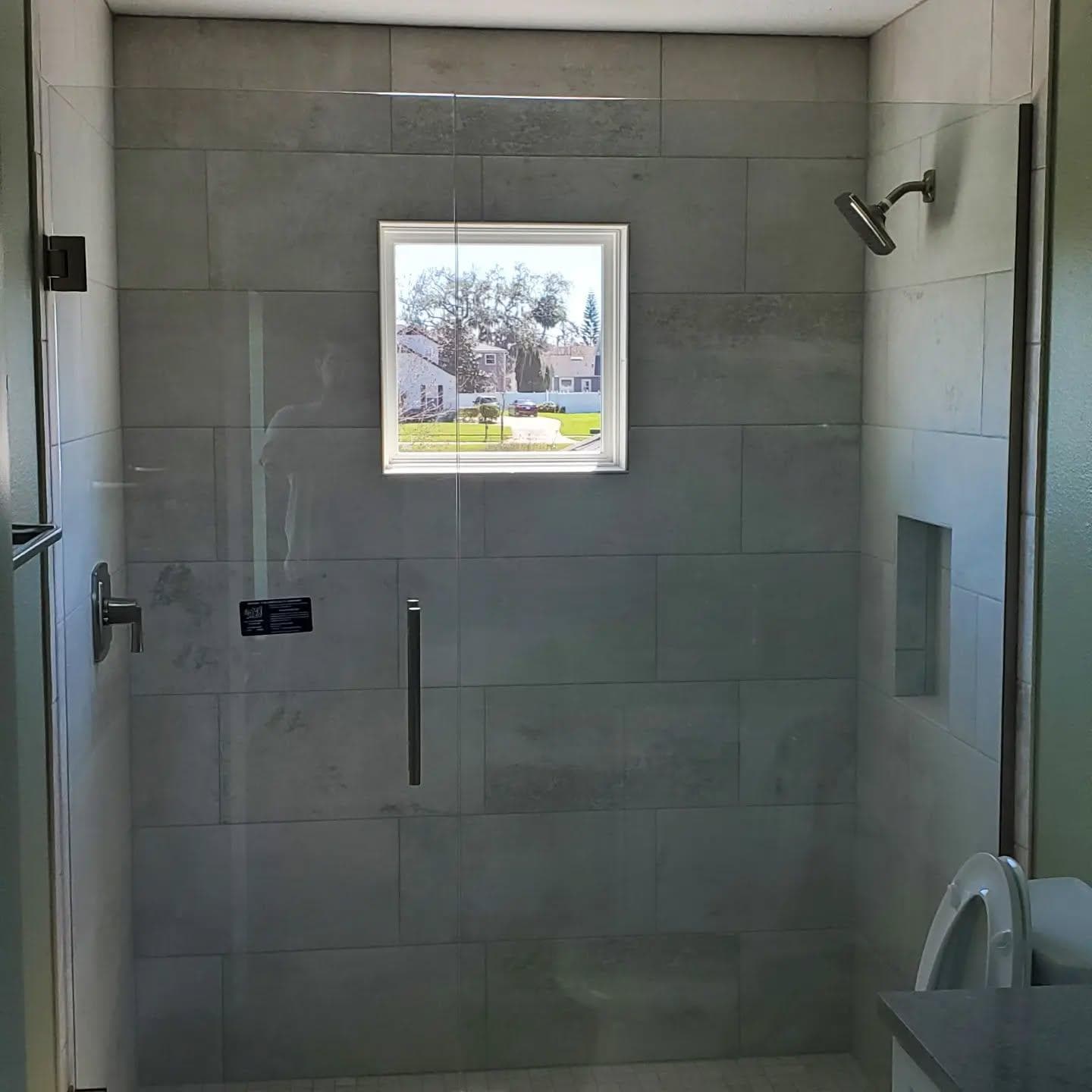 Frameless glass shower door with large-format gray tile