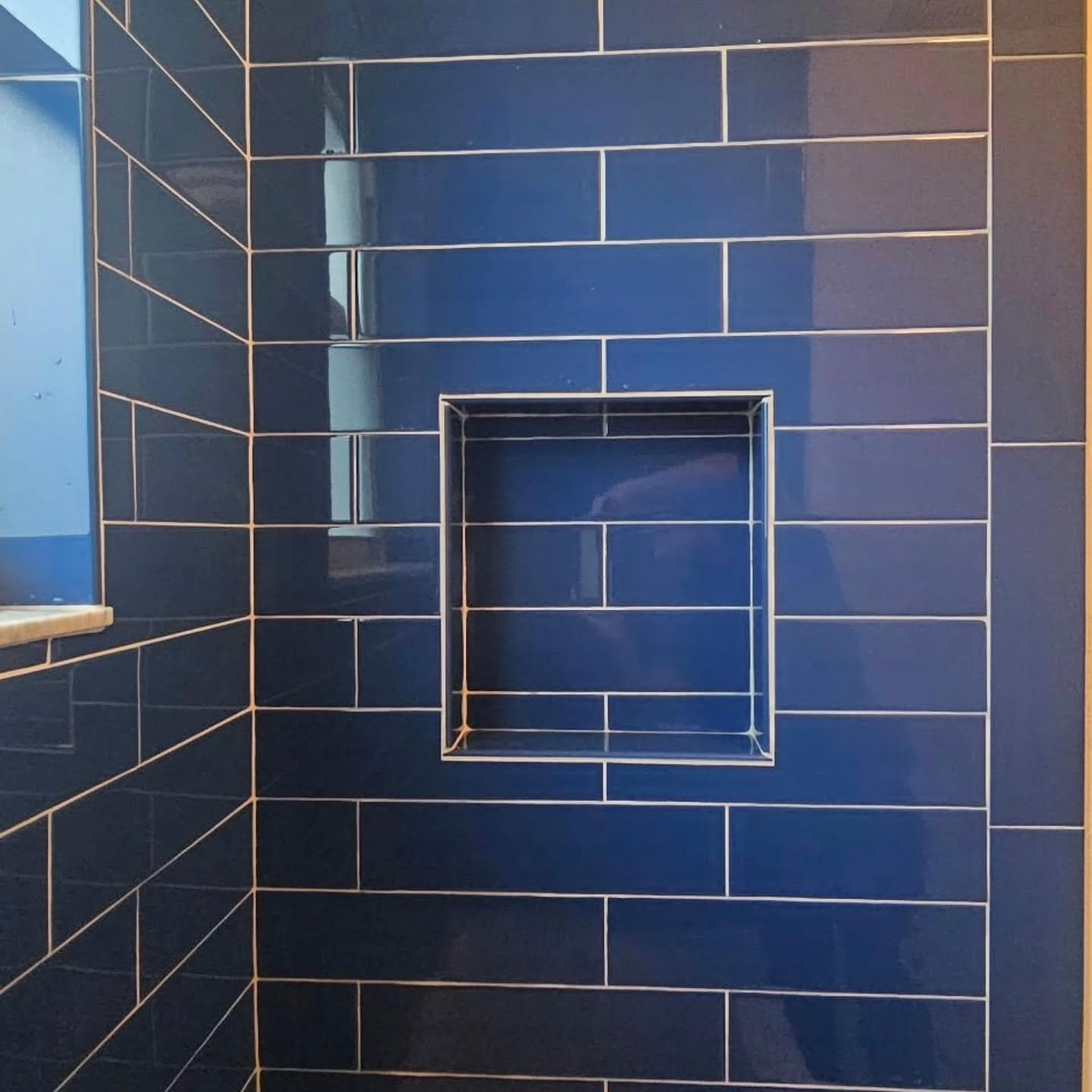 Deep blue subway tile shower wall with niche