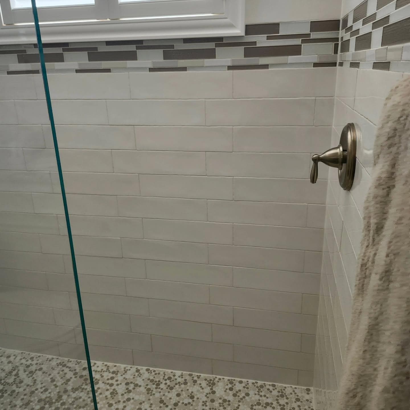 Two-tone tile shower with pebble mosaic floor