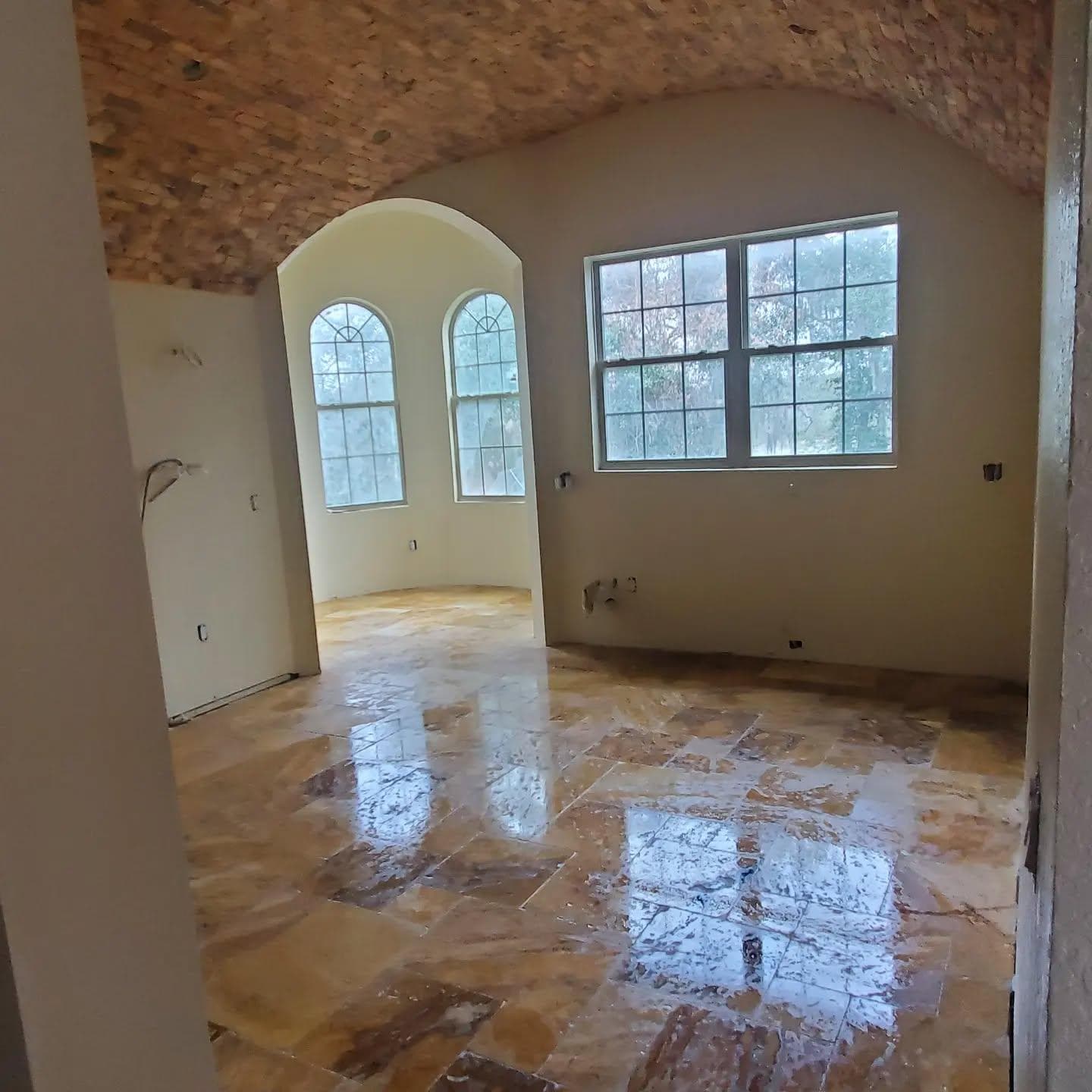 Vaulted ceiling room with arched windows and marble tile flooring